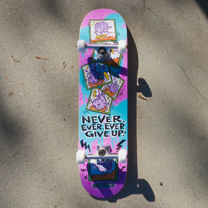 The colorful Never Give Up complete skateboard with pink, purple, and blue graphic design. Featuring a cartoon of Neuro, an anthropomorphic brain, riding their skateboard down stairs and eating it. Features the motivational quote, "Never, Ever, Ever, Give Up!"