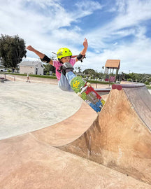 Child skateboarding at a park with a clear blue sky
