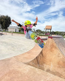 Child skateboarding at a park with a clear blue sky